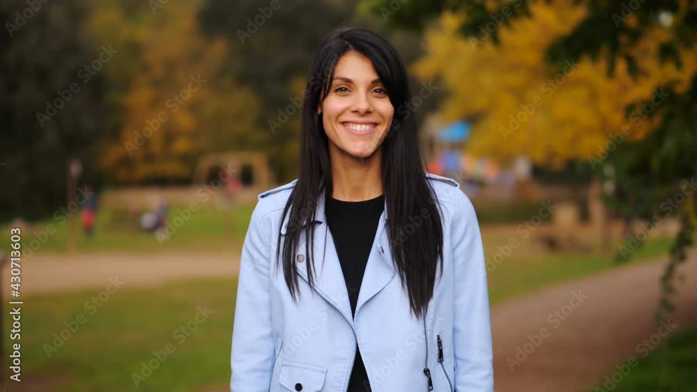 youth, confidence - serious girl at park changes expression and smiles at camera youth, confidence - serious girl at park changes expression and smiles at camera