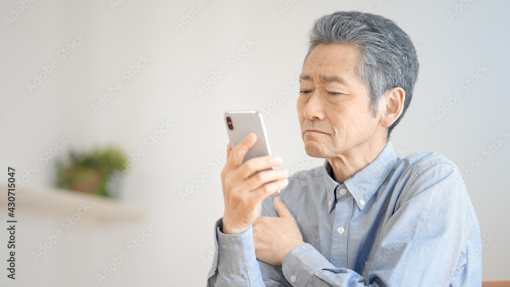 スマートフォンの操作に悪戦苦闘するシニア男性 スマートフォンの操作に悪戦苦闘するシニア男性