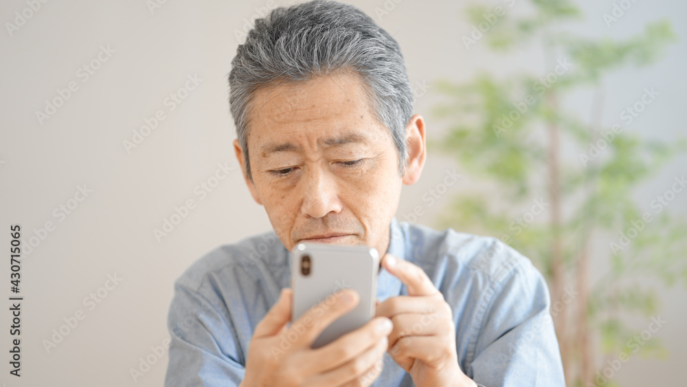 スマートフォンの操作に悪戦苦闘するシニア男性 スマートフォンの操作に悪戦苦闘するシニア男性