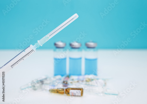 Monochromatic image of glass vials and a syringe. Plastic medical syringe and vial vaccine. A syringe is injected into a vial. Coronavirus vaccination and immunization concept. Fight pandemic.