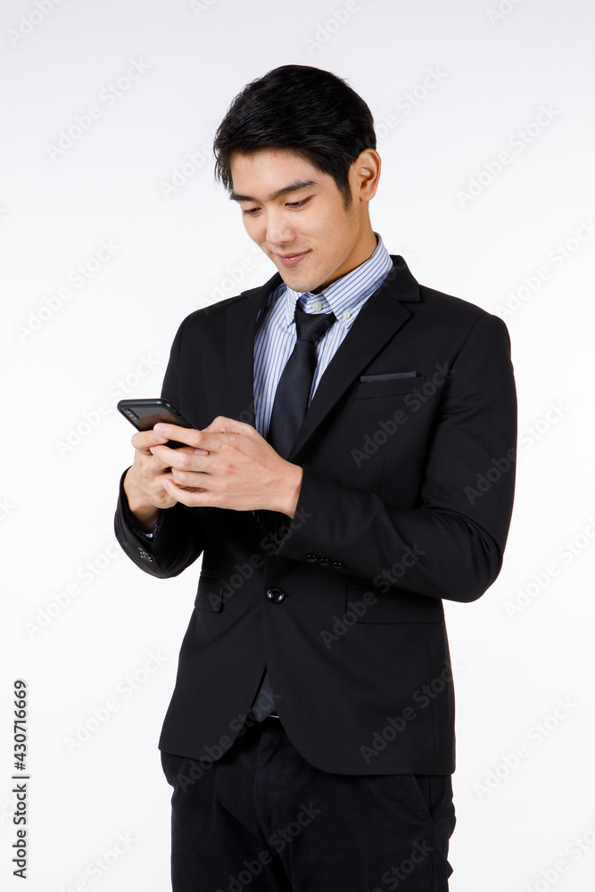 Portrait shot of Asian young black short hair executive lawyer manager in formal suit with necktie standing smiling look at mobile smartphone in hand checking message in front of white background Portrait shot of Asian young black short hair executive lawyer manager in formal suit with necktie standing smiling look at mobile smartphone in hand checking message in front of white background
