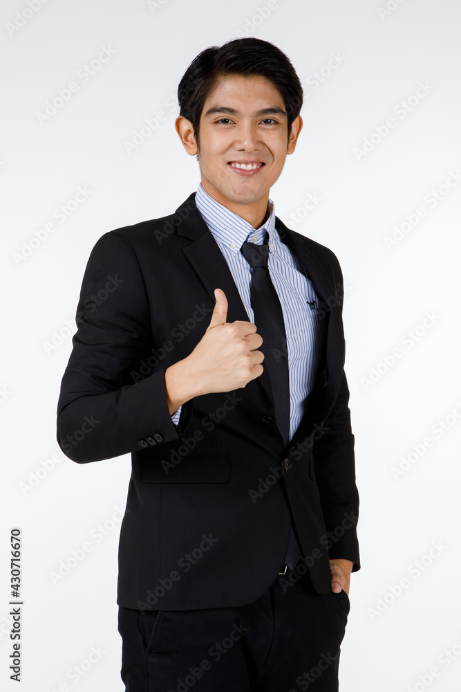 Portrait shot of Asian young happy confident white collar businessman in black stylish modern formal suit standing smiling look at camera showing thumb up admiring in front of white background Portrait shot of Asian young happy confident white collar businessman in black stylish modern formal suit standing smiling look at camera showing thumb up admiring in front of white background
