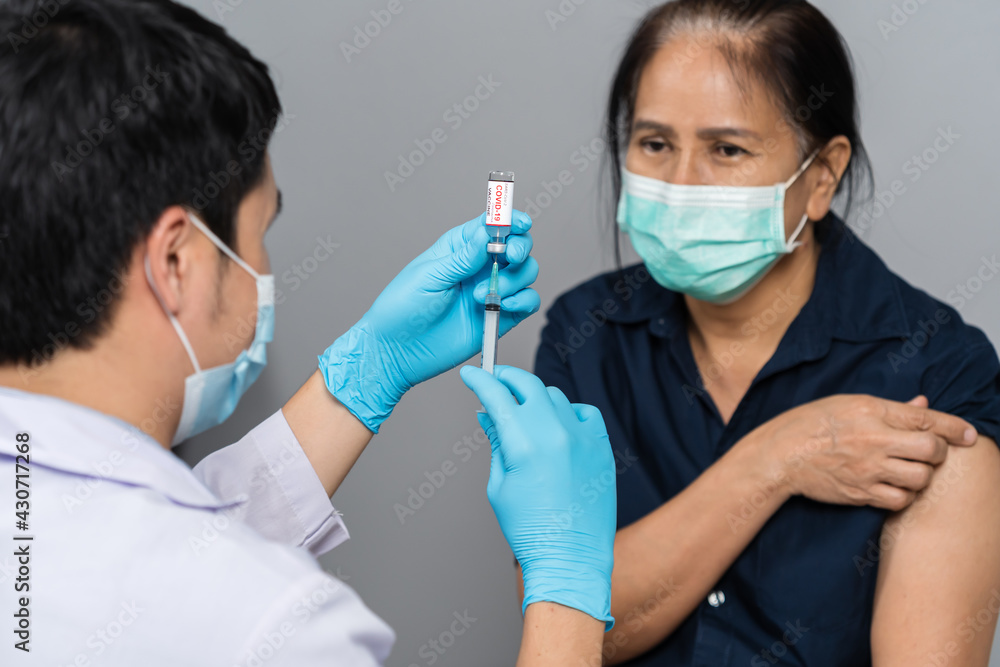 doctor draws medication out of vial before injection with syringe to woman and wearing medical mask. Covid-19 or coronavirus vaccine doctor draws medication out of vial before injection with syringe to woman and wearing medical mask. Covid-19 or coronavirus vaccine