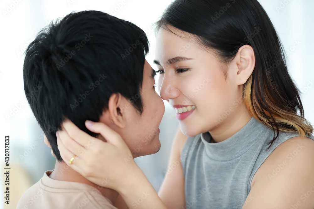 Portrait shot of cute smiling young Asian lover couple looking at each other eye with passion and kissing together by mouths. Wife and husband sharing a romantic moment on Saint Valentine's Day. Portrait shot of cute smiling young Asian lover couple looking at each other eye with passion and kissing together by mouths. Wife and husband sharing a romantic moment on Saint Valentine's Day.