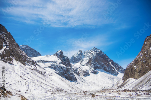 Idyllic winter landscape with hiking trail in the mountains. Rocks, snow and stones in mountain valley view. Mountain panorama. © sergfear