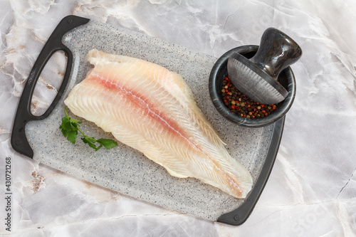 Fillet of raw pangasius fish with spices on cutting board photo