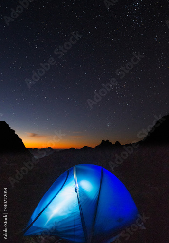 Tent at night below stars. Distant Mount Hayes. Western Arthur Range, Southwest National Park, Tasmania. World Heritage Area