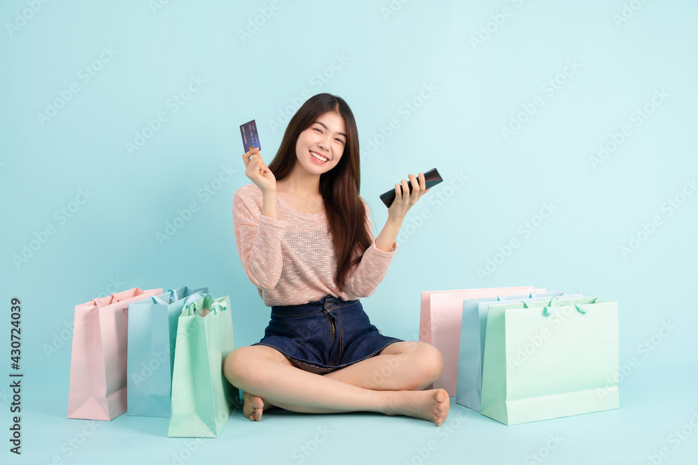 Online Order. Asian girl sitting with smart phone using credit card shopping online on blue background shopping online concept Stock Photo Adobe Stock
