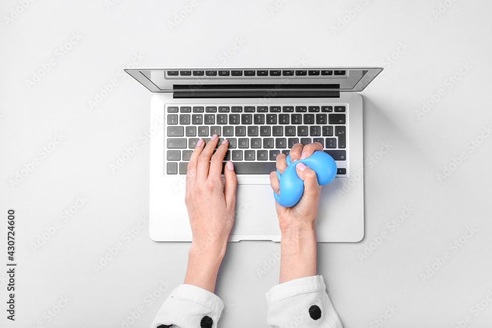 Woman squeezing stress ball while working with laptop on white background Woman squeezing stress ball while working with laptop on white background