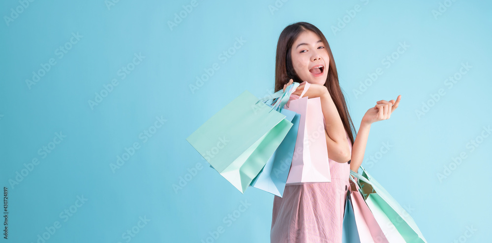 portrait of cheerful young brunette woman holding credit card and shopping bags over Blue background. shopaholic Concept portrait of cheerful young brunette woman holding credit card and shopping bags over Blue background. shopaholic Concept