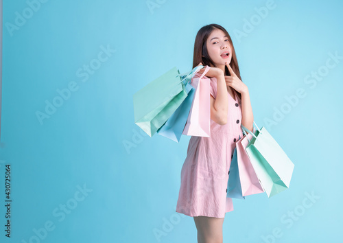 portrait of cheerful young brunette woman holding credit card and shopping bags over Blue background. shopaholic Concept