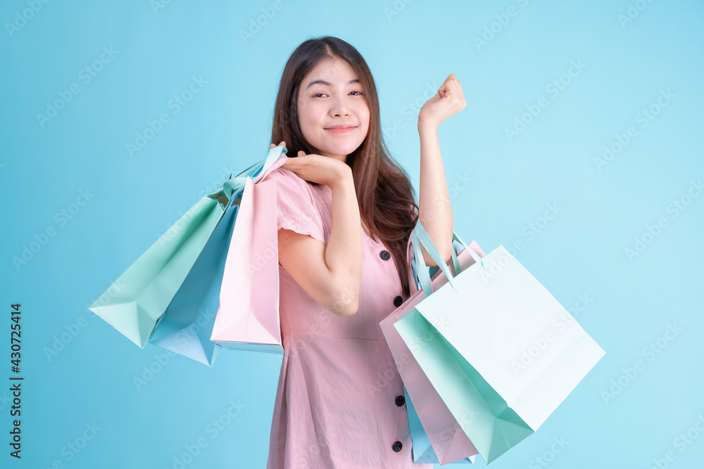 portrait of cheerful young brunette woman holding credit card and shopping bags over Blue background. shopaholic Concept portrait of cheerful young brunette woman holding credit card and shopping bags over Blue background. shopaholic Concept