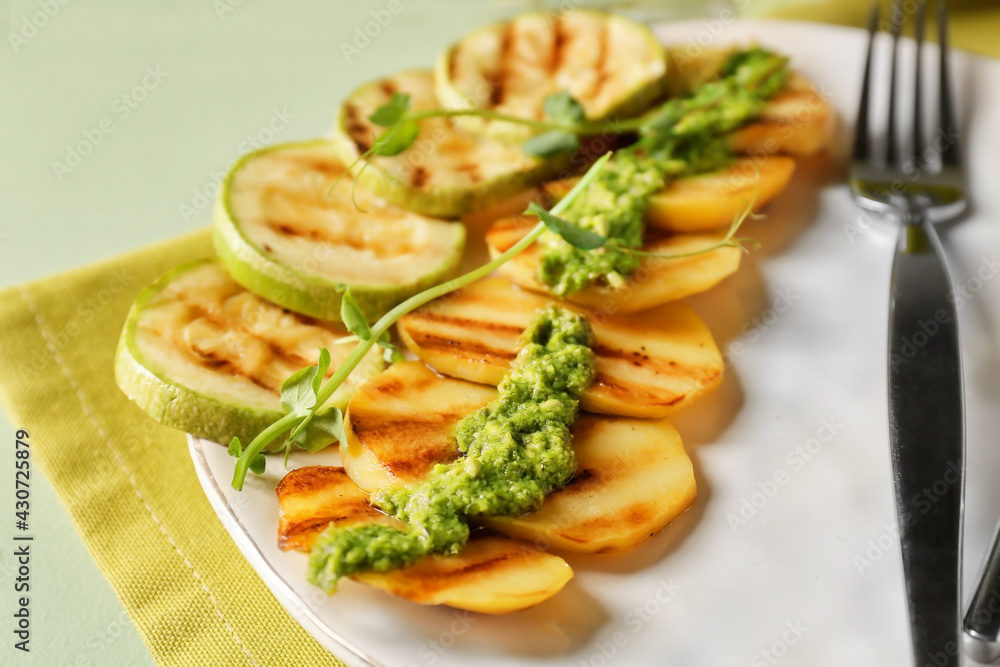 Tasty grilled vegetables with pesto sauce on color wooden background, closeup