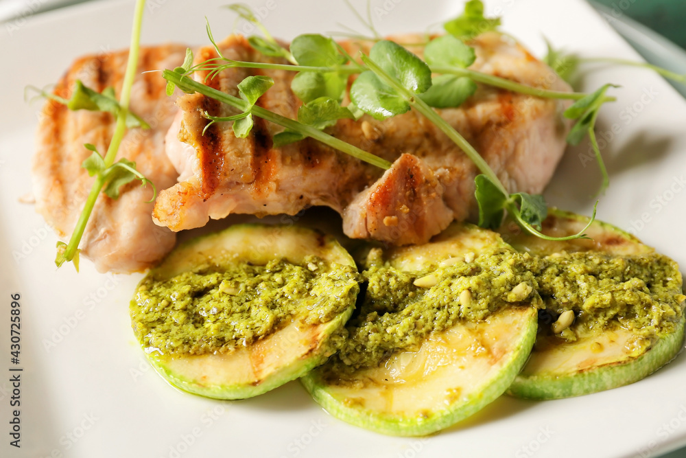 Plate with tasty grilled chicken meat, zucchini and pesto sauce, closeup