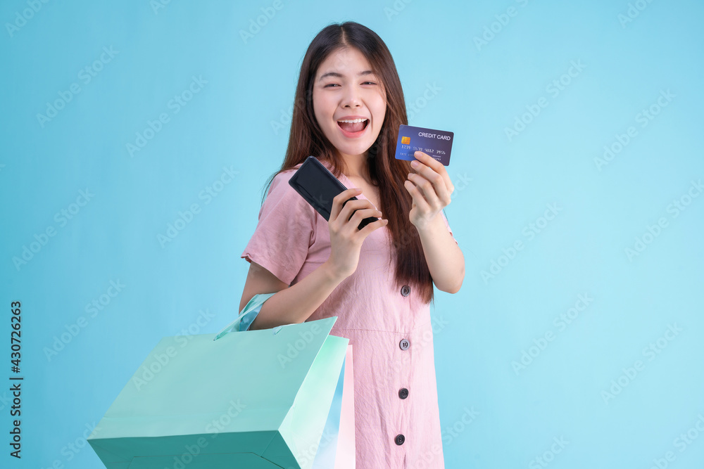 portrait of cheerful young brunette woman holding credit card and shopping bags over Blue background. shopaholic Concept portrait of cheerful young brunette woman holding credit card and shopping bags over Blue background. shopaholic Concept
