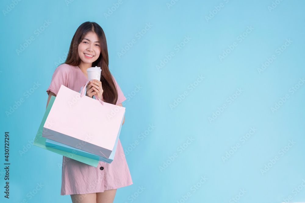 portrait of cheerful young brunette woman holding credit card and shopping bags over Blue background. shopaholic Concept portrait of cheerful young brunette woman holding credit card and shopping bags over Blue background. shopaholic Concept