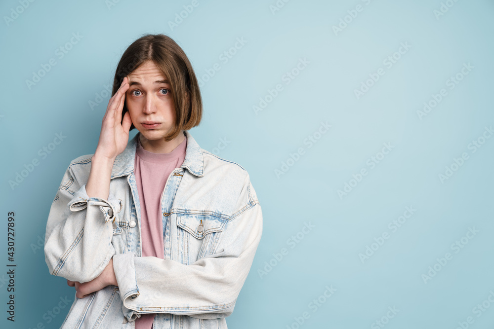 Young confused man frowning and covering his face while looking at camera Young confused man frowning and covering his face while looking at camera