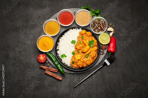 Plate of Traditional Chicken Curry and set of spices on dark concrete background