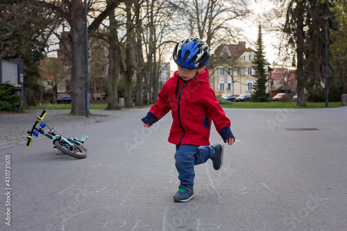 Cute child, toddler boy, playing hopscotch, running and riding bike in the park