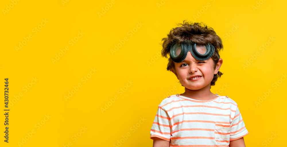 Cute stylish kid in pilot glasses isolated on yellow background. Child dreams to be a pilot and playing with plane. Vintage aviator concept. Kindergarten or school boy want to fly. Innovation Cute stylish kid in pilot glasses isolated on yellow background. Child dreams to be a pilot and playing with plane. Vintage aviator concept. Kindergarten or school boy want to fly. Innovation