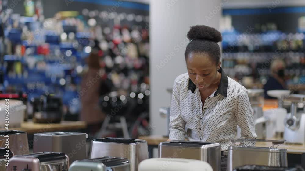 shopping in home appliances store, black lady is viewing toaster, woman is choosing equipment for kitchen and cooking, shopping in home appliances store, black lady is viewing toaster, woman is choosing equipment for kitchen and cooking,