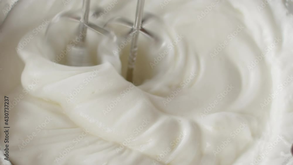 Male chef in black gloves whips egg whites with mixer in iron bowl in restaurant kitchen Male chef in black gloves whips egg whites with mixer in iron bowl in restaurant kitchen