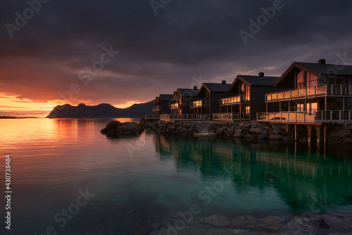 Houses on the rocky shore of the Norwegian sea during a red sunset