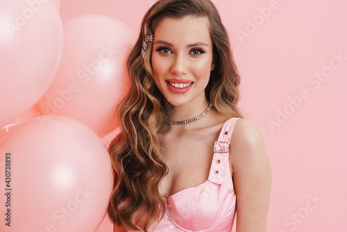 Young white woman wearing dress smiling while posing with balloons