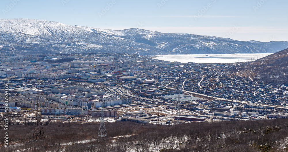 View of the city of Magadan. Landscape with a seaside town. Top view of the streets and buildings. In the distance there is a sea bay and mountains. Magadan, Magadan Region, Siberia, Far East Russia.