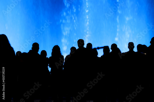 Silhouettes of people at the blue fountain at night.