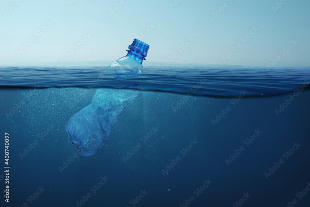 Garbage plastic bottle floats in blue sea water with underwater