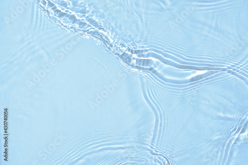 De-focused blurred transparent blue colored clear calm water surface texture with splashes and bubbles. Trendy abstract nature background. Water waves in sunlight with copy space.