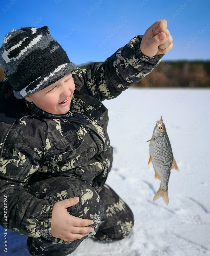 The boy caught a fish on ice in winter. The boy caught a fish on ice in winter.