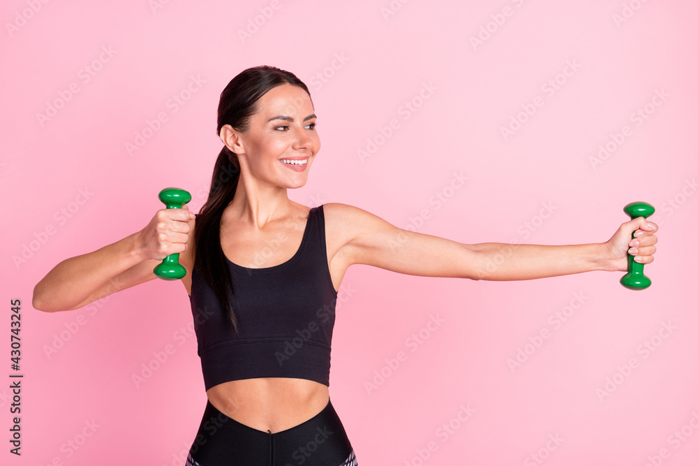 Photo of confident positive young woman dressed sportive outfit smiling training holding dumbbells isolated pink color background Photo of confident positive young woman dressed sportive outfit smiling training holding dumbbells isolated pink color background