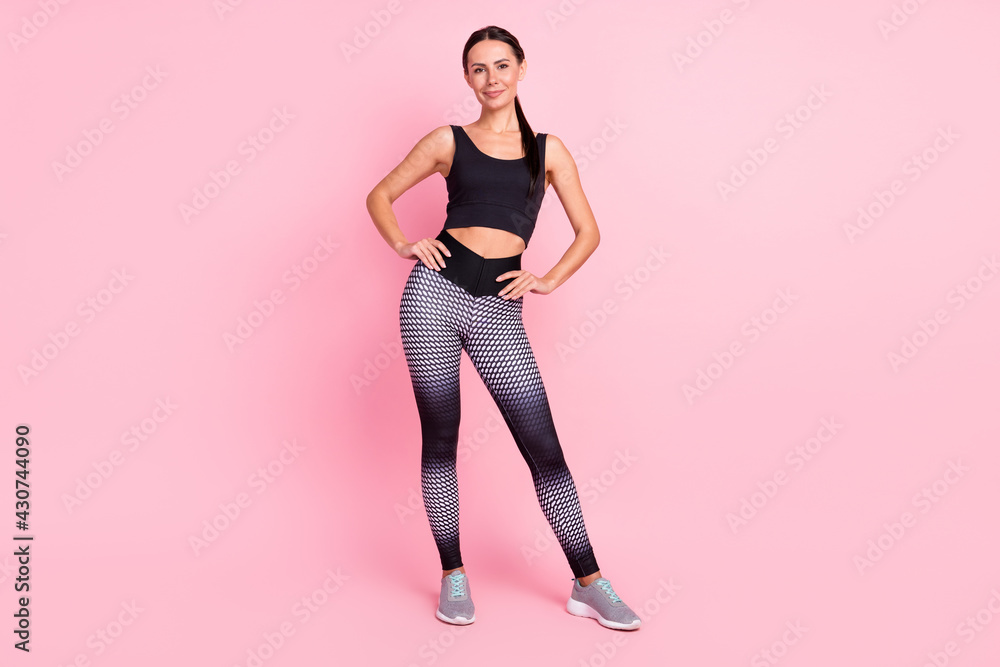 Photo of sweet cute young woman dressed sportive arms hands waist smiling standing isolated pink color background Photo of sweet cute young woman dressed sportive arms hands waist smiling standing isolated pink color background