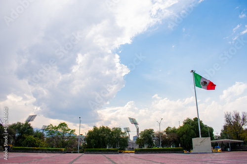 Wavy Mexican flag in public square with a cloudy sky as background