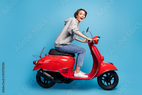 Full length body size photo of girl driving motorcycle isolated bright blue color background