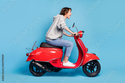 Full length body size photo of crazy excited girl driving fast motorbike delivery isolated vibrant blue color background