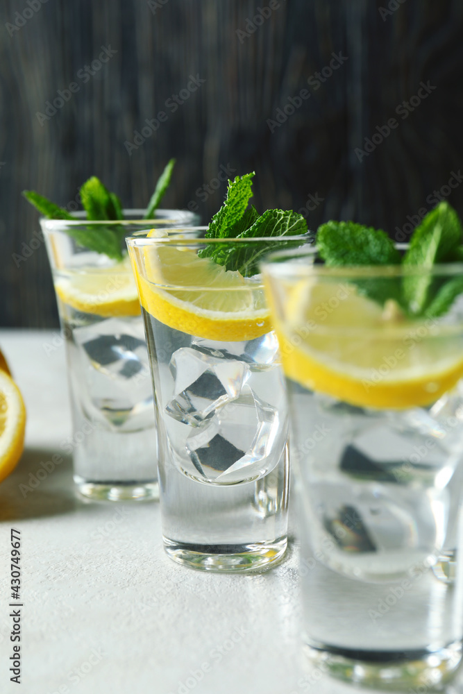 Shots with lemon slice and mint on white textured table Shots with lemon slice and mint on white textured table