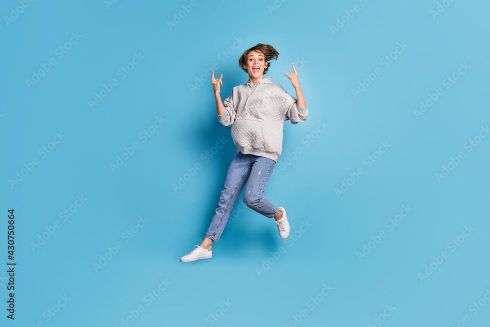 Full length body size side profile photo of girl jumping high showing heavy metal sign isolated vivid blue color background