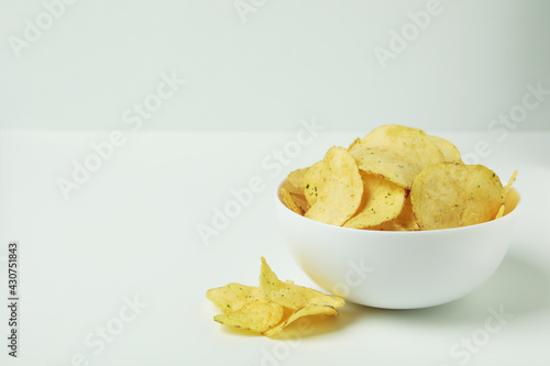 Bowl with potato chips on white background
