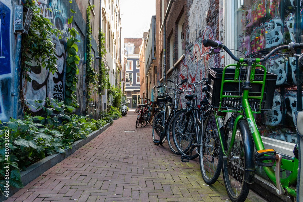 Row of bicycles parked in empty alley with graffiti on the walls