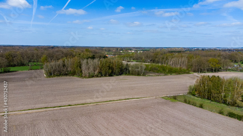 Aerial view with a drone of a spring wavy agricultural countryside landscape with plowed and unplowed fields and trees in the blue evening sky. High quality photo photo