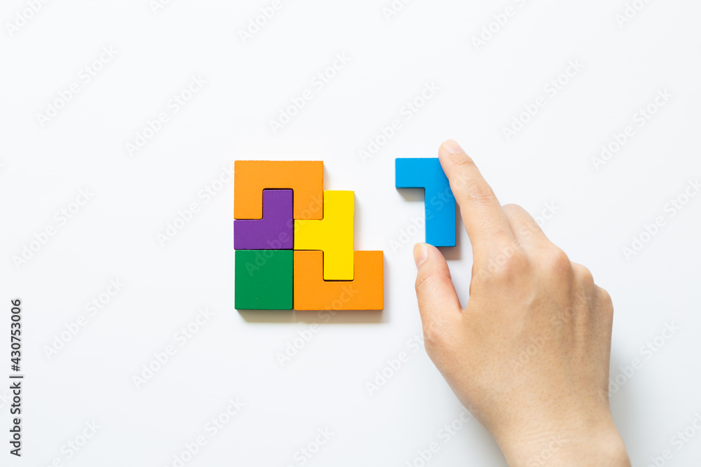 Set of color blocks puzzle pieces and hand holding last one piece on white background. Creative thinking, idea, problem solving, success concept. top view