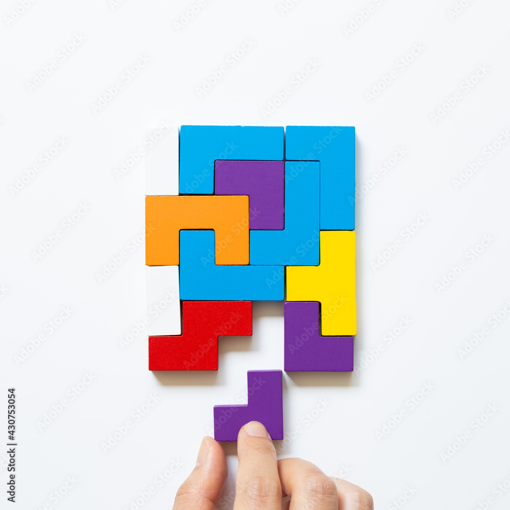 Set of color blocks puzzle pieces and hand holding last one piece on white background. Creative thinking, idea, problem solving, success concept. top view Set of color blocks puzzle pieces and hand holding last one piece on white background. Creative thinking, idea, problem solving, success concept. top view