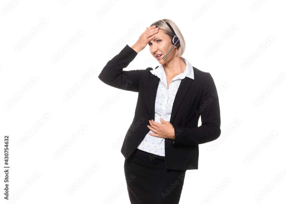 Burnout at work. Attractive adult caucasian woman in formal wear with headset and microphone touch her head and stomach with hands and looks bad and tired, isolated on white. Burnout at work. Attractive adult caucasian woman in formal wear with headset and microphone touch her head and stomach with hands and looks bad and tired, isolated on white.