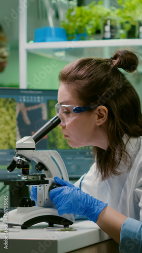 Biologist taking leaf sample putting into microscope observing chemical liquid. Scientist engineering analyzing organic gmo plants while researching in microbiology food laboratory