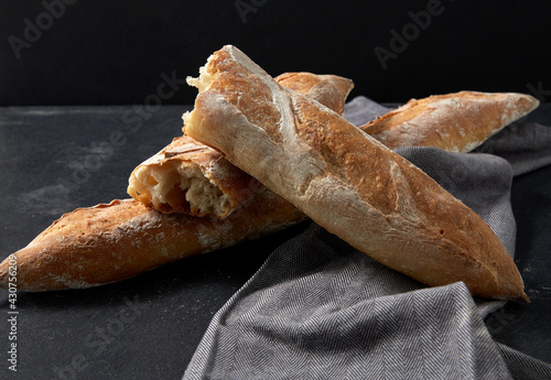 food, baking and cooking concept - close up of baguette bread on kitchen towel photo