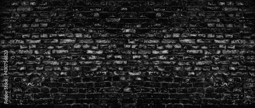 Black old shabby brick wall wide texture. Dark gray rough brickwork. Aged block masonry backdrop. Gloomy grunge abstract panoramic background