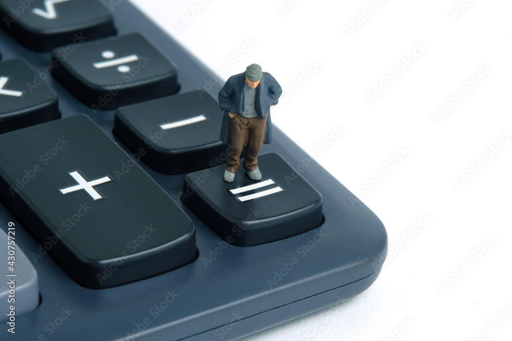 Poor man with no money left standing above calculator. Miniature tiny people toys photography. isolated on white background. Poor man with no money left standing above calculator. Miniature tiny people toys photography. isolated on white background.
